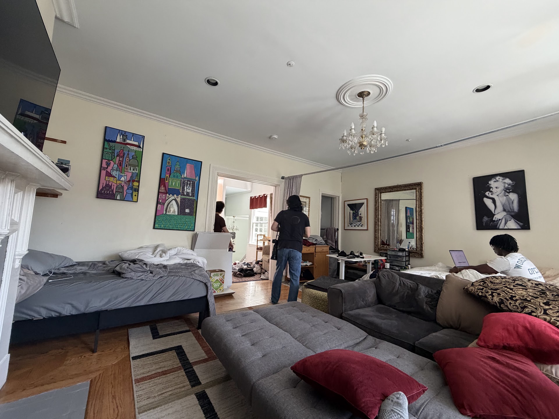 The living room with residents, bedding, boxes, and red couch cushions the day the Journal photographed the house
