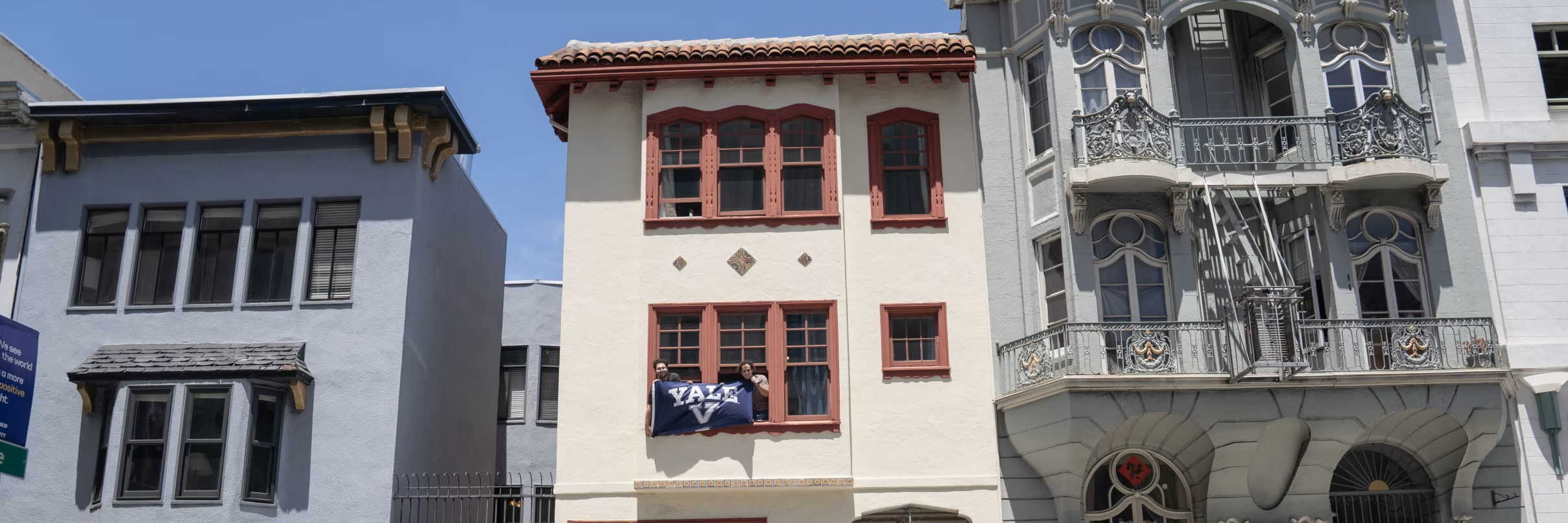Residents holding a Yale flag from the Pine Street window, in the original color photograph
